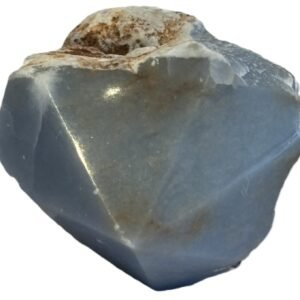 Natural rough angelite freeform crystal with unpolished sides and a smooth polished blue point standing on a white background